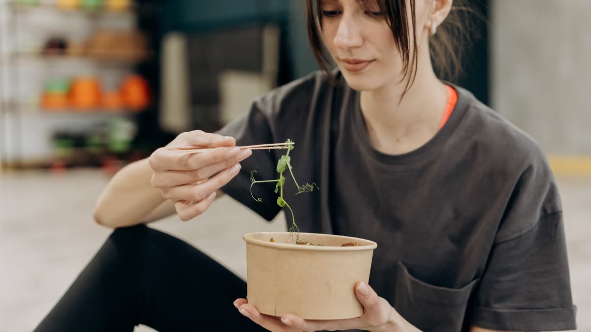 Young woman enjoying a healthy salad indoors, focusing on balanced nutrition and healthy living.